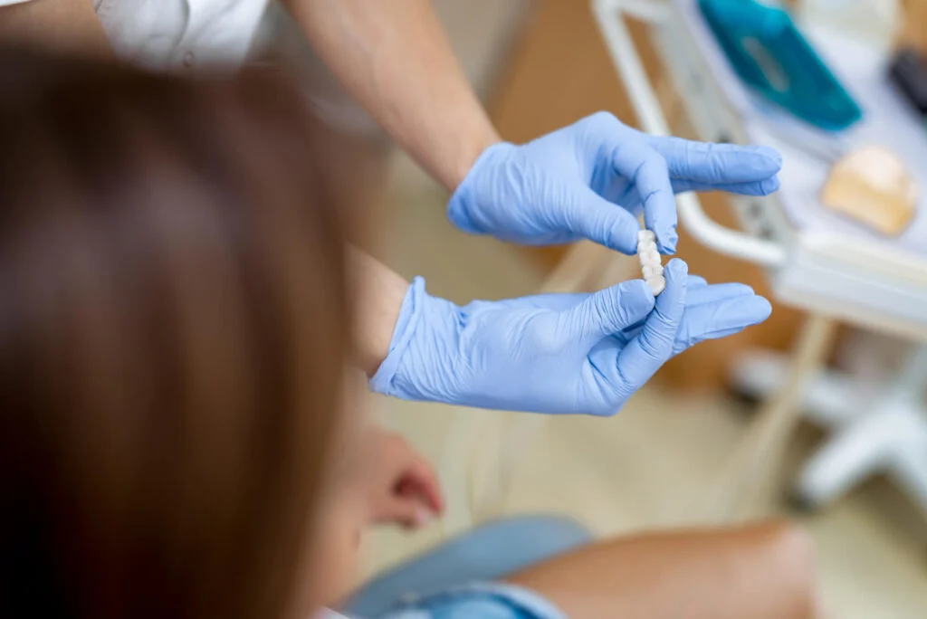 Dentist in Auburn holding a dental crown and showing it to a patient